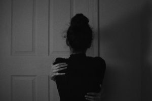 woman in black dress standing near white wooden door